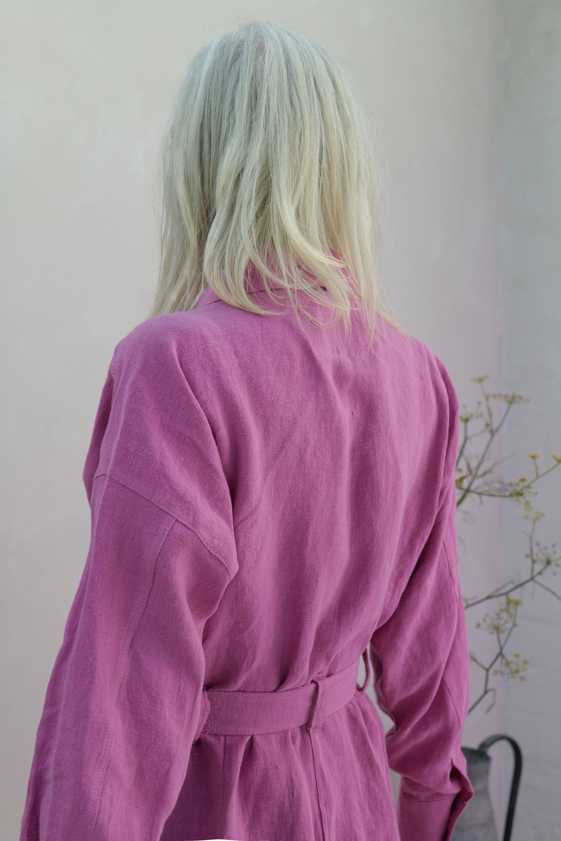 Person wearing a pink linen jumpsuit with a neutral background